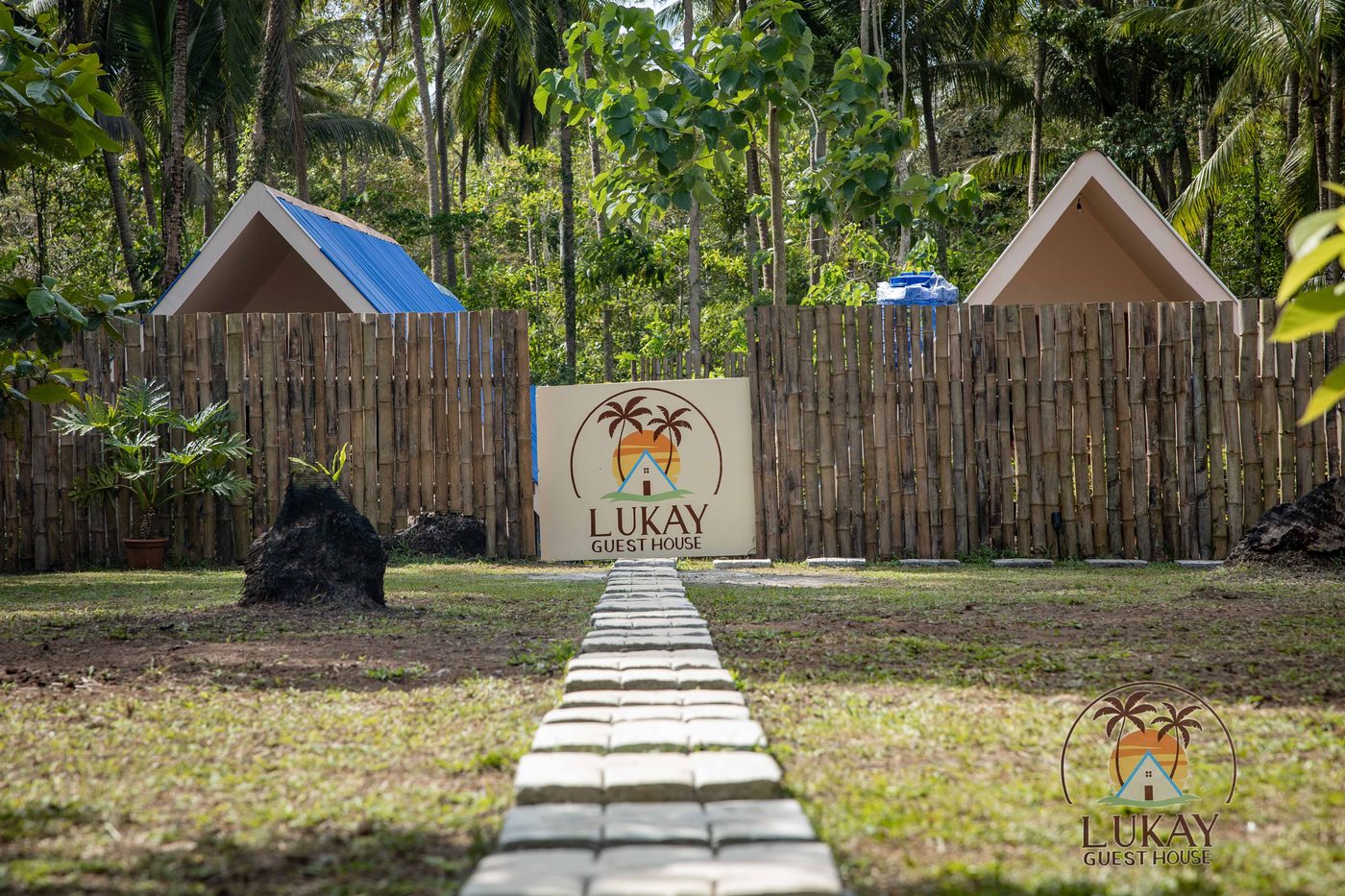 The Lukay Guest House sign along the palm-lined entrance path