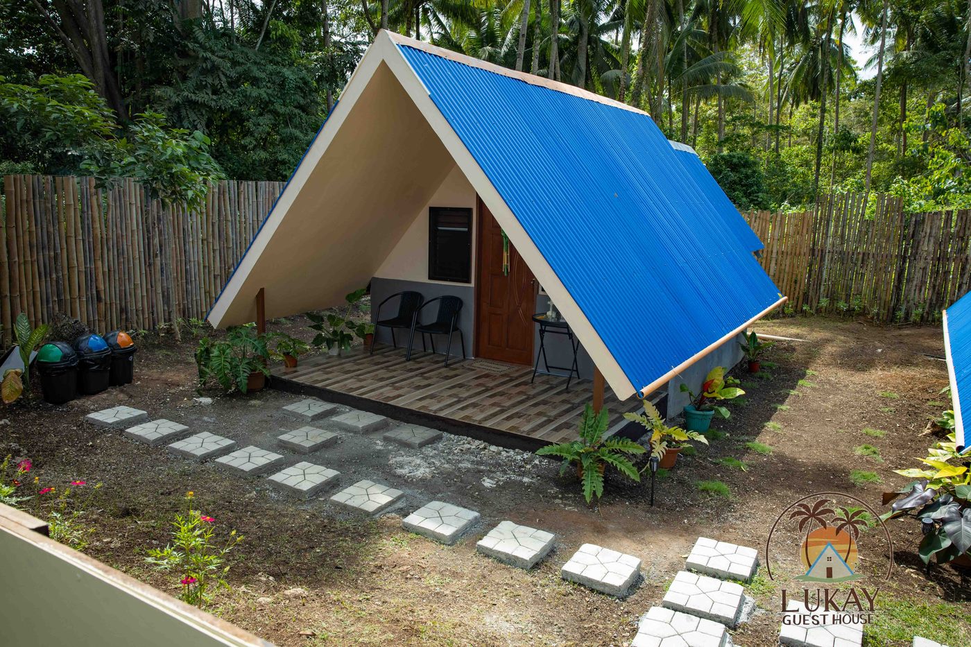 The blue-roofed A-frame cabin set in its tropical garden